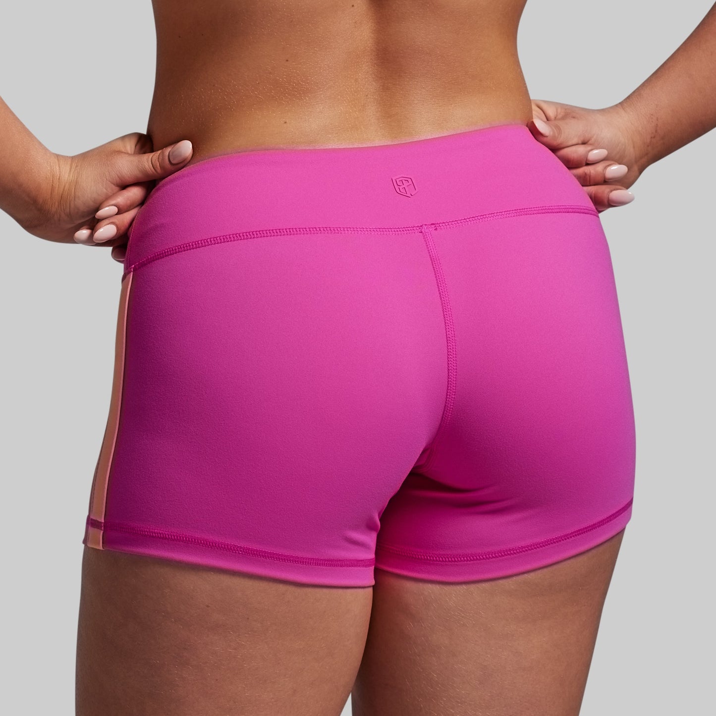 Person wearing bright pink athletic shorts on a plain background
