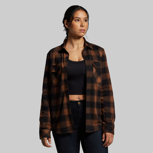 Woman wearing a plaid shirt over a black top on a gray background