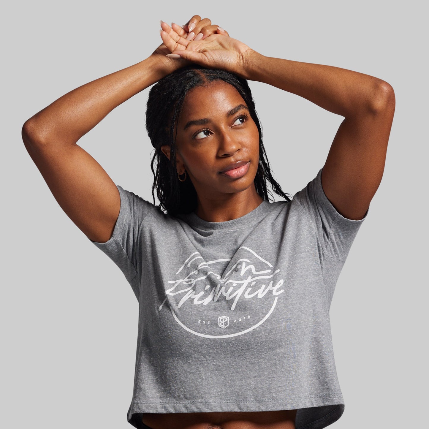 Woman wearing a gray t-shirt with a logo and text on a plain background