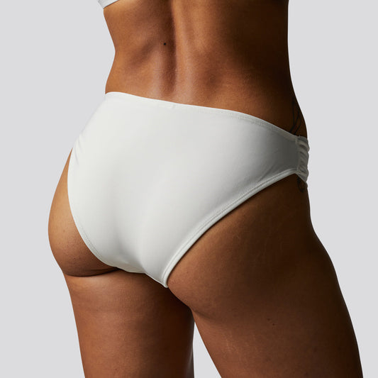 White bikini bottom worn by a person on a plain background
