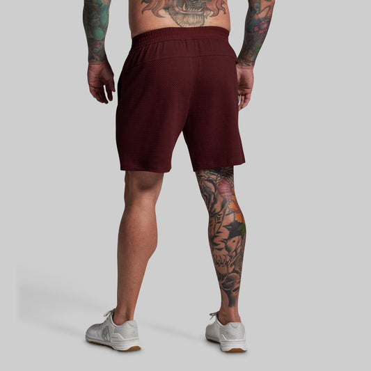 Person wearing maroon shorts on a plain background