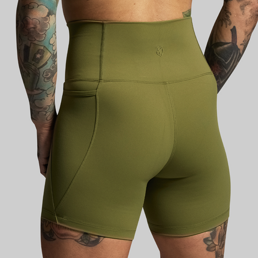 Green athletic shorts worn by a person with tattoos on a gray background