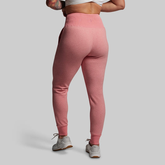 Person wearing pink textured joggers on a plain background