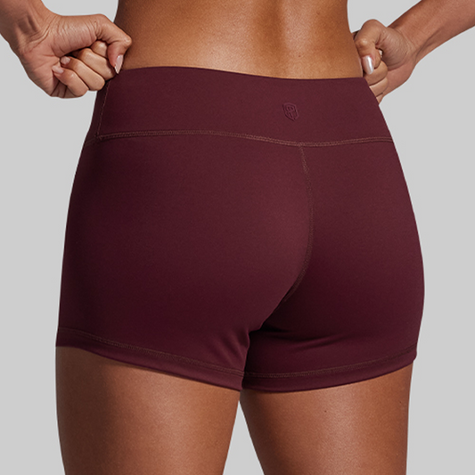 Maroon athletic shorts worn by a person on a gray background