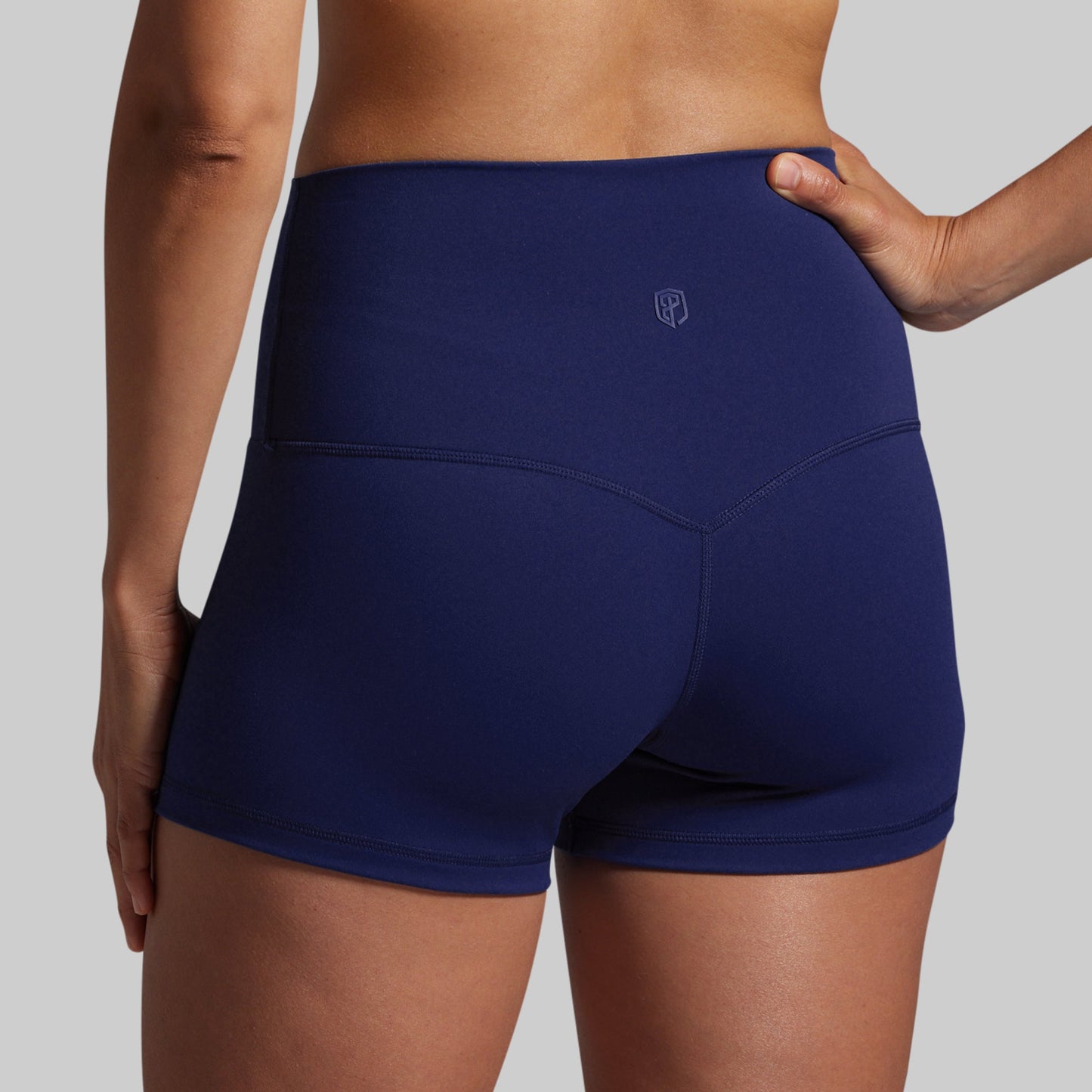 Navy blue athletic shorts worn by a person on a gray background