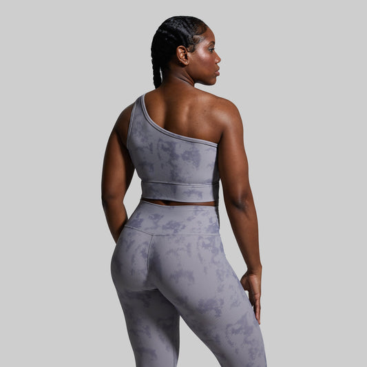 Person wearing a gray sports bra with a subtle pattern on a plain background
