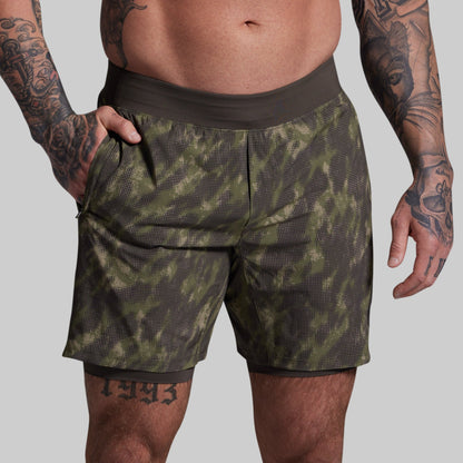 Person wearing green camouflage shorts on a gray background