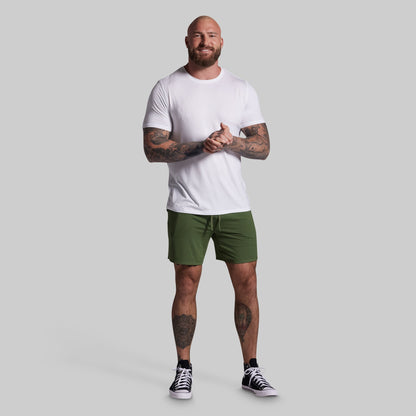 Man wearing a white t-shirt and green shorts on a gray background