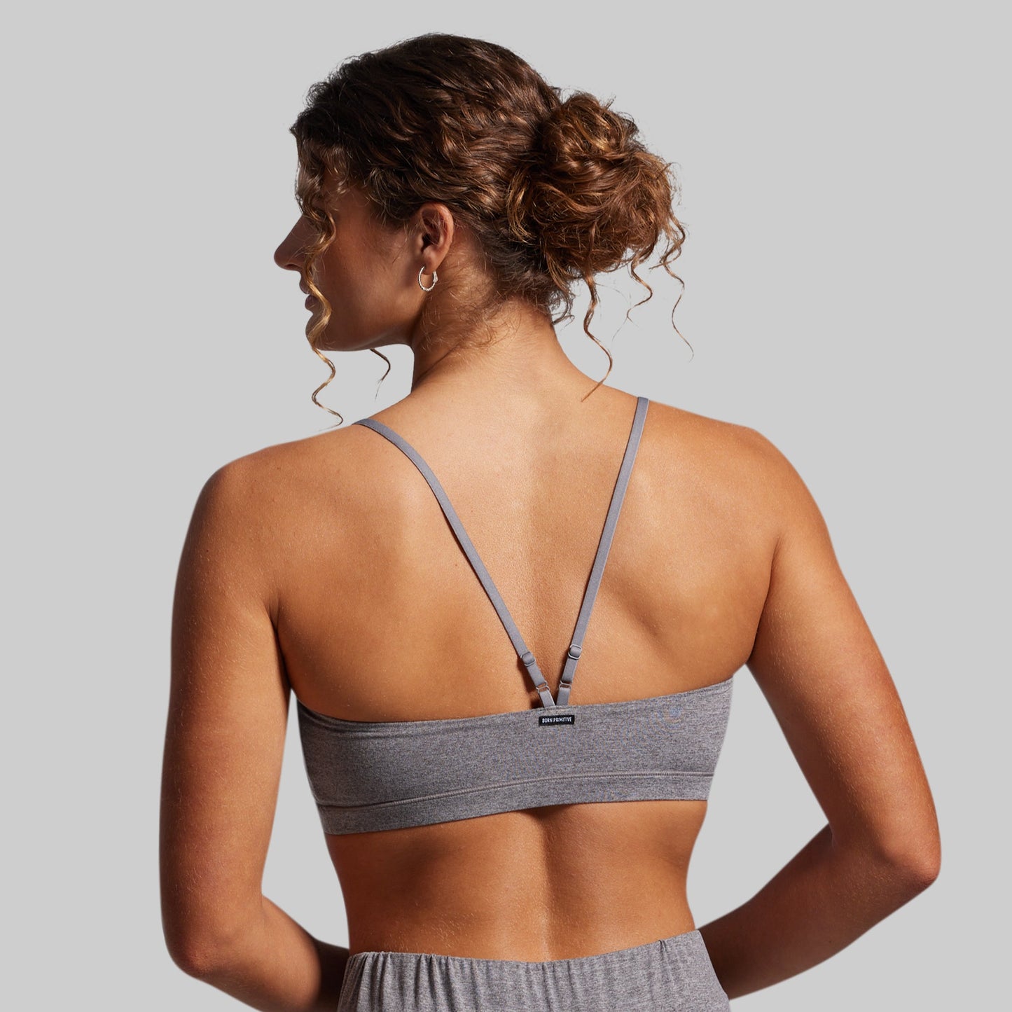 Woman wearing a gray sports bra and shorts on a plain background