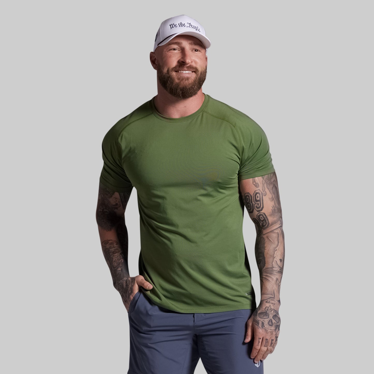 Man wearing a green t-shirt and white cap on a gray background