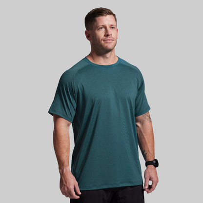 Man wearing a teal athletic shirt on a gray background
