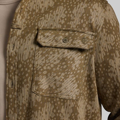 Close-up of a patterned button-up shirt with a chest pocket, featuring a tan and brown abstract brushstroke design.