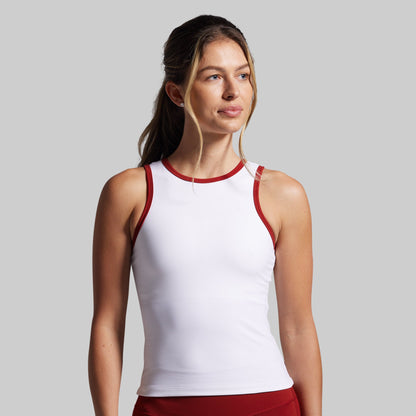Woman wearing a white tank top with red trim against a gray background