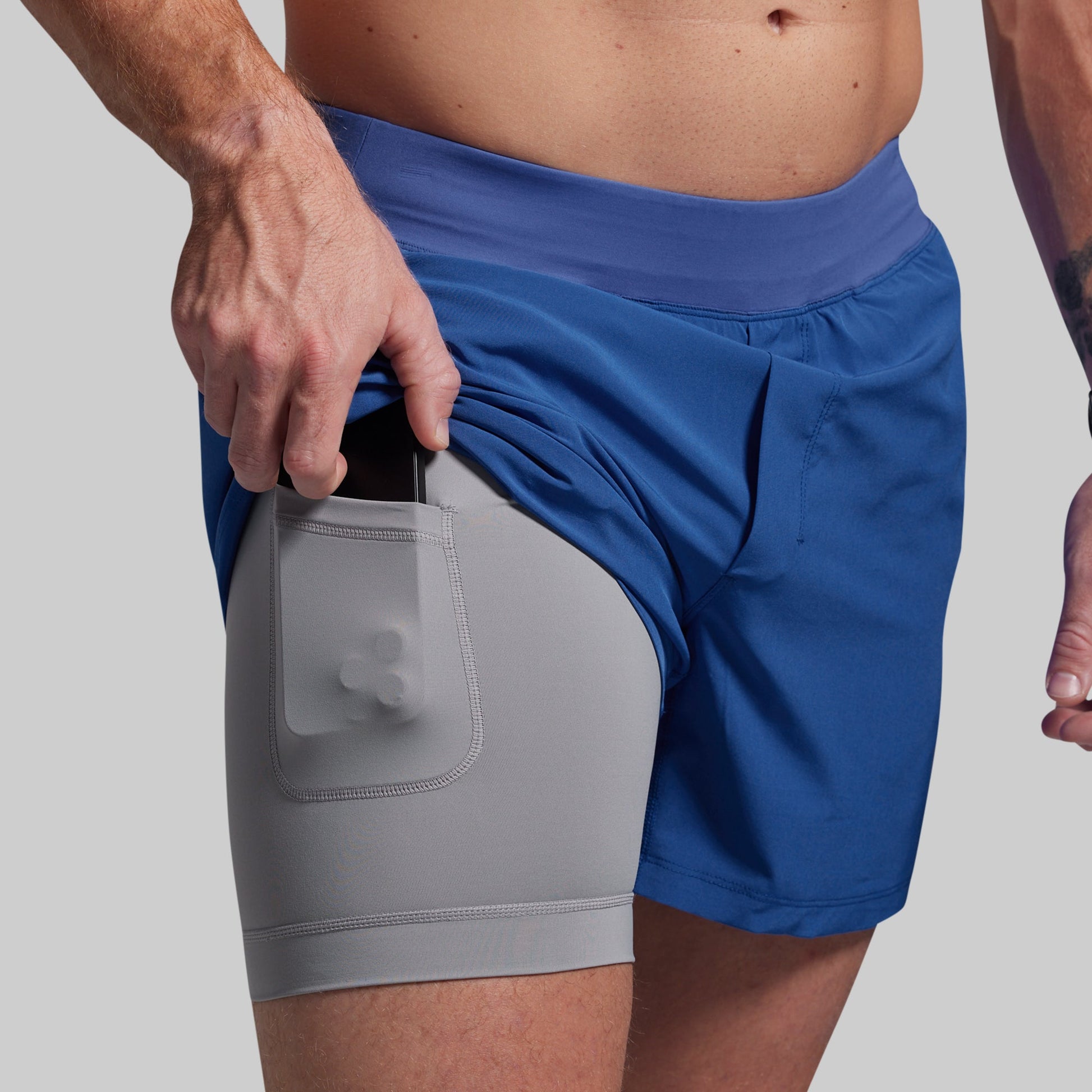 Two-tone shorts with a gray bottom and blue top on a neutral background
