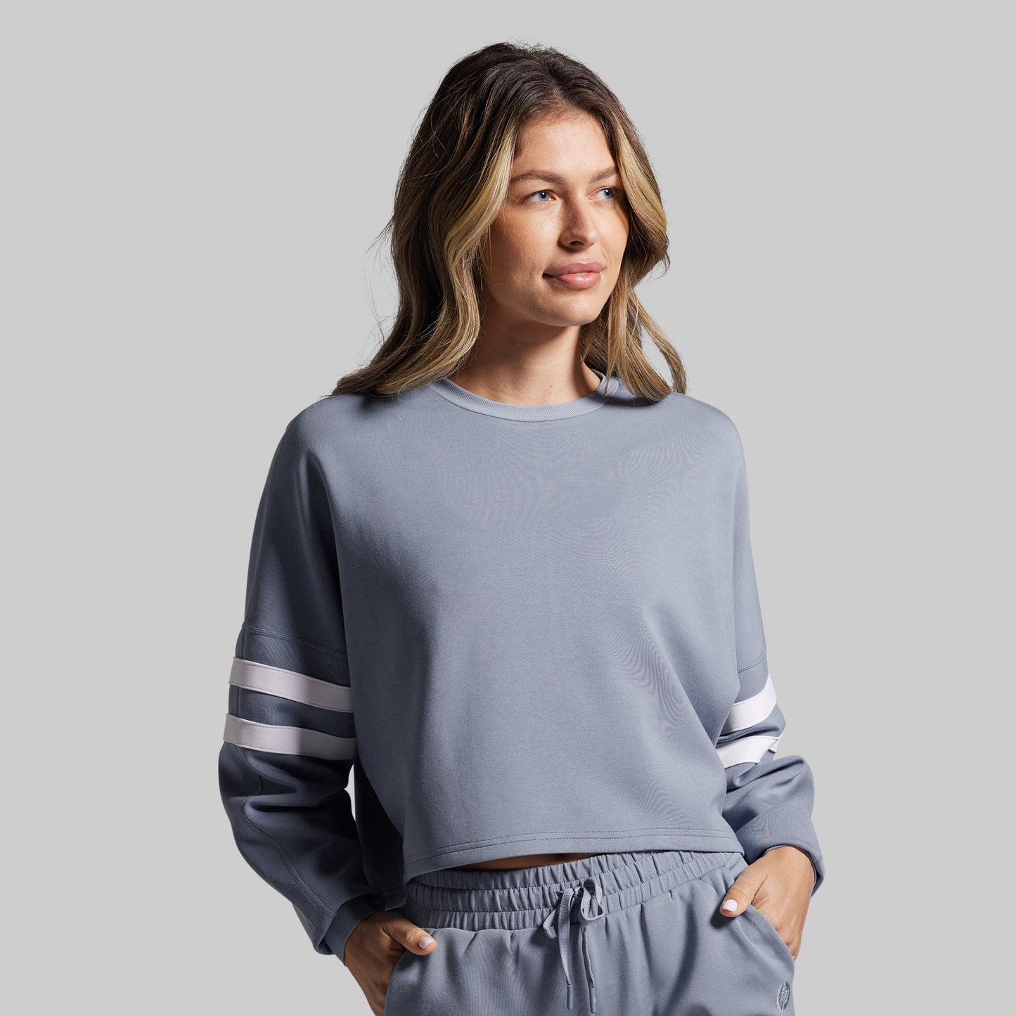 Woman wearing a gray sweatshirt with white stripes on a gray background