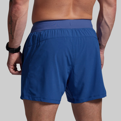 Blue athletic shorts worn by a person on a plain background