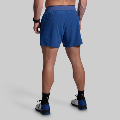 Person wearing blue athletic shorts on a gray background