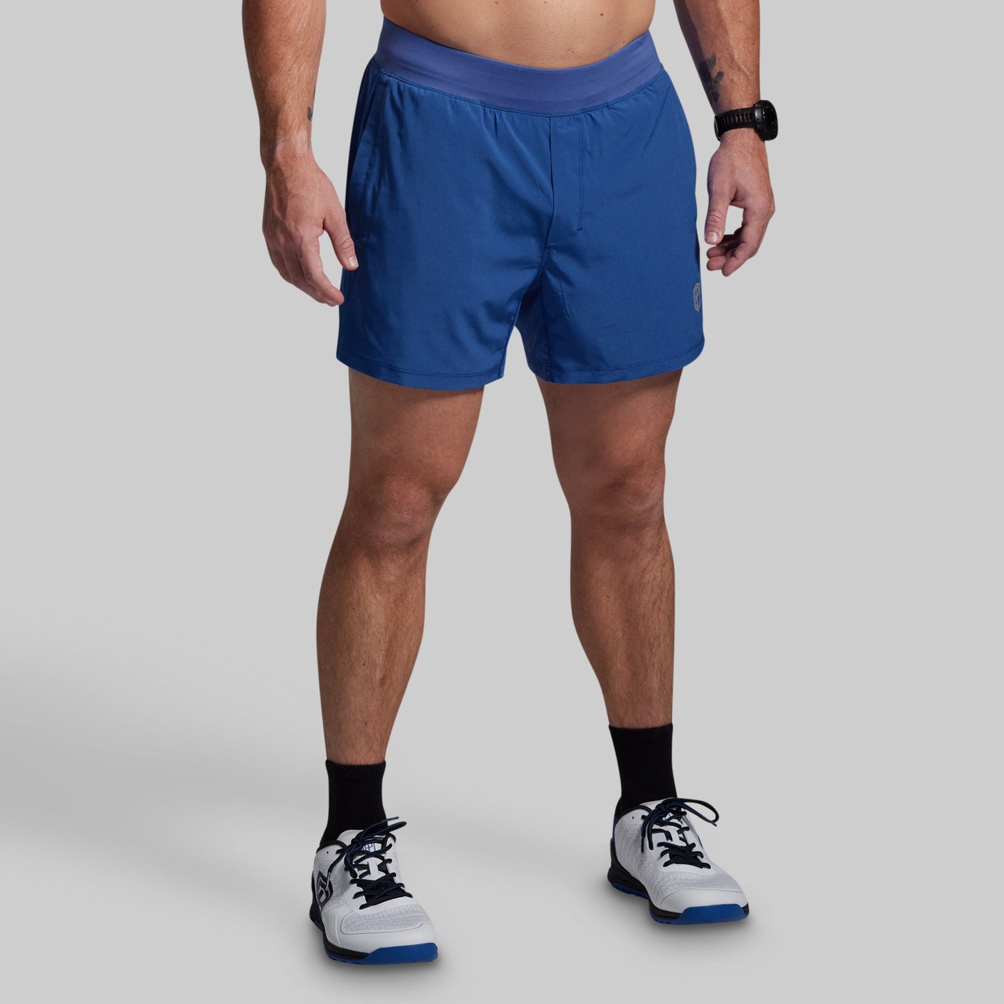 Person wearing blue athletic shorts on a gray background