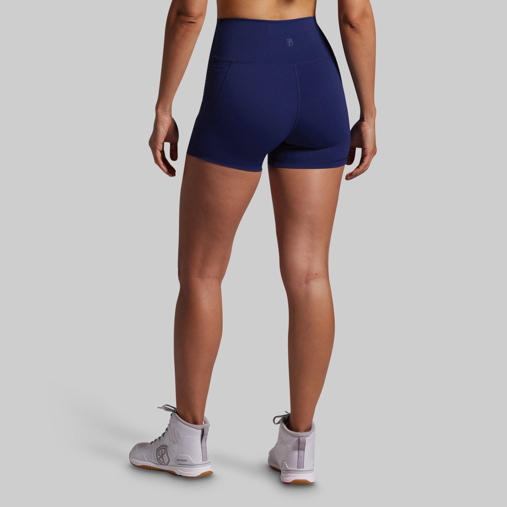 Person wearing navy blue athletic shorts on a gray background