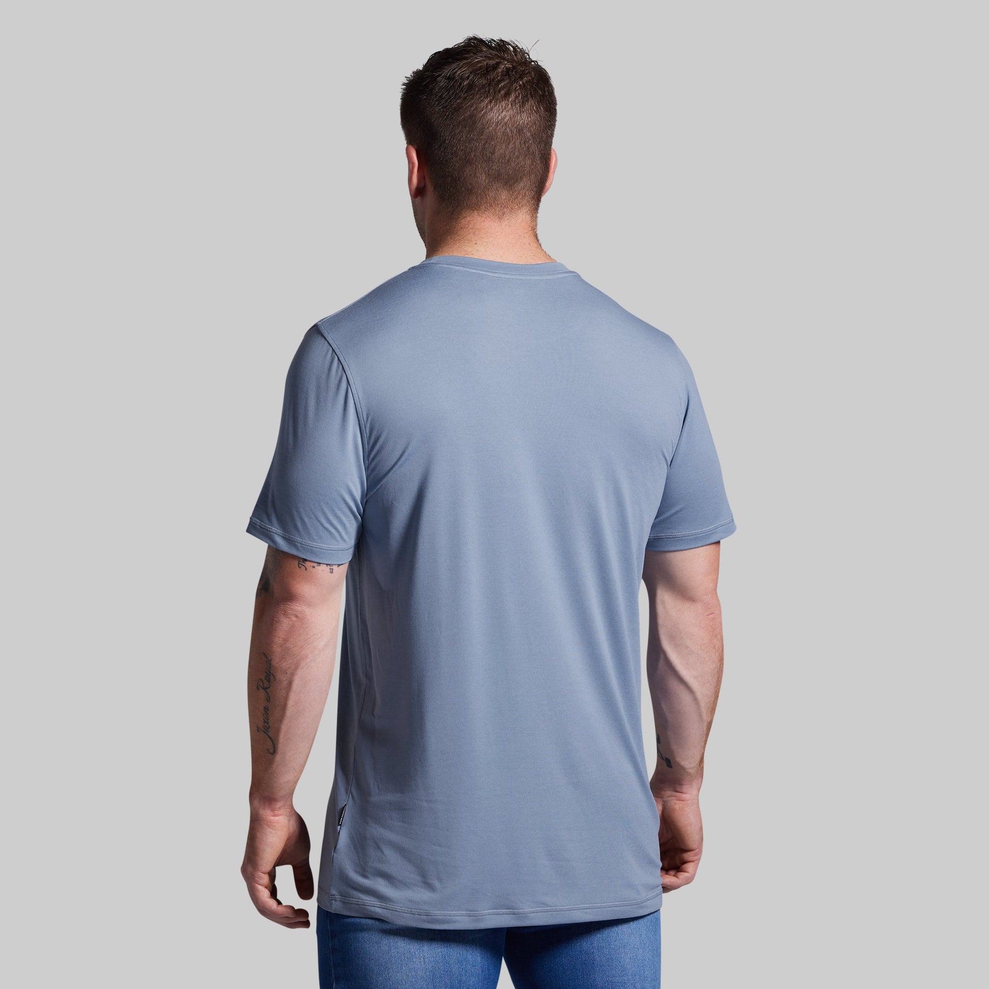 Man wearing a light blue t-shirt against a gray background