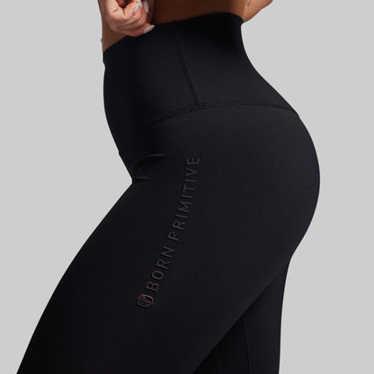 Black leggings with 'Born Primitive' branding on a gray background