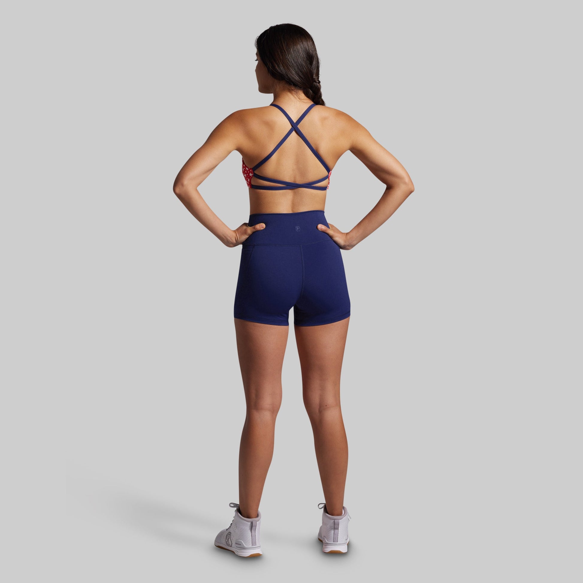 Person wearing a blue sports bra and shorts on a gray background