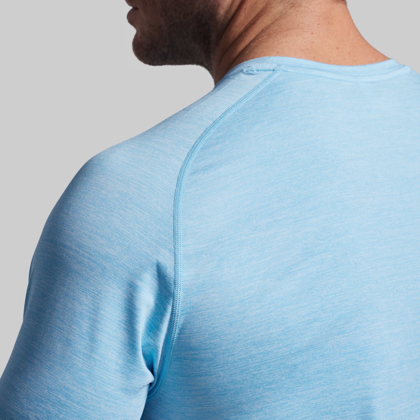 Close-up of a person wearing a light blue athletic shirt on a gray background