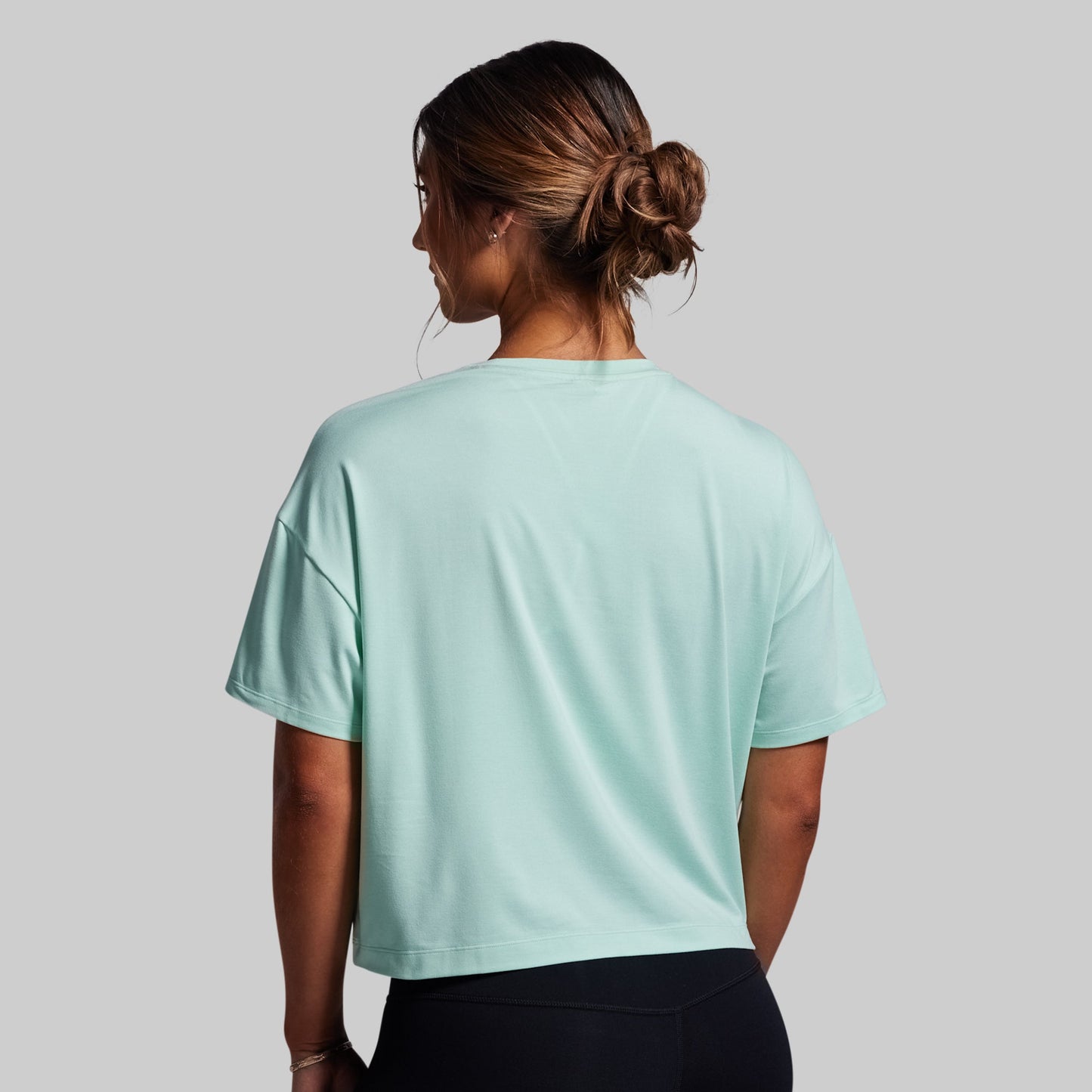 Person wearing a light blue t-shirt on a gray background