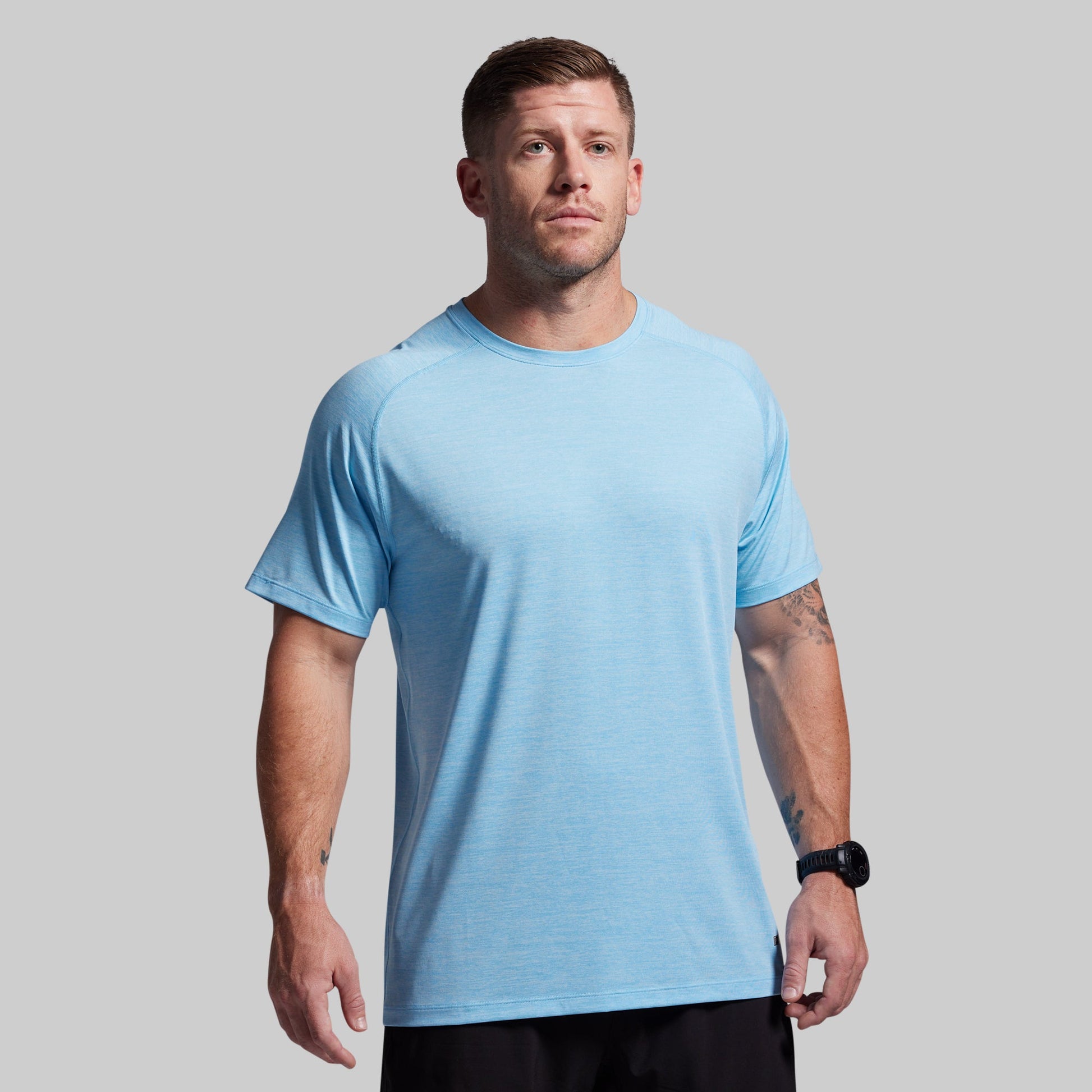 Man wearing a light blue t-shirt against a gray background