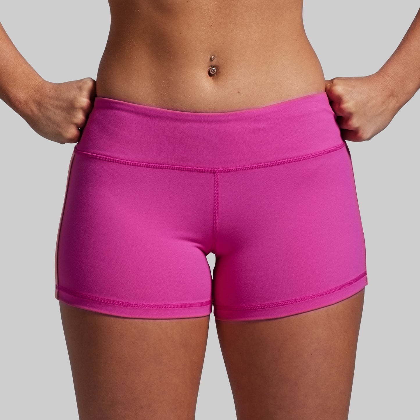 Person wearing bright pink athletic shorts on a plain background