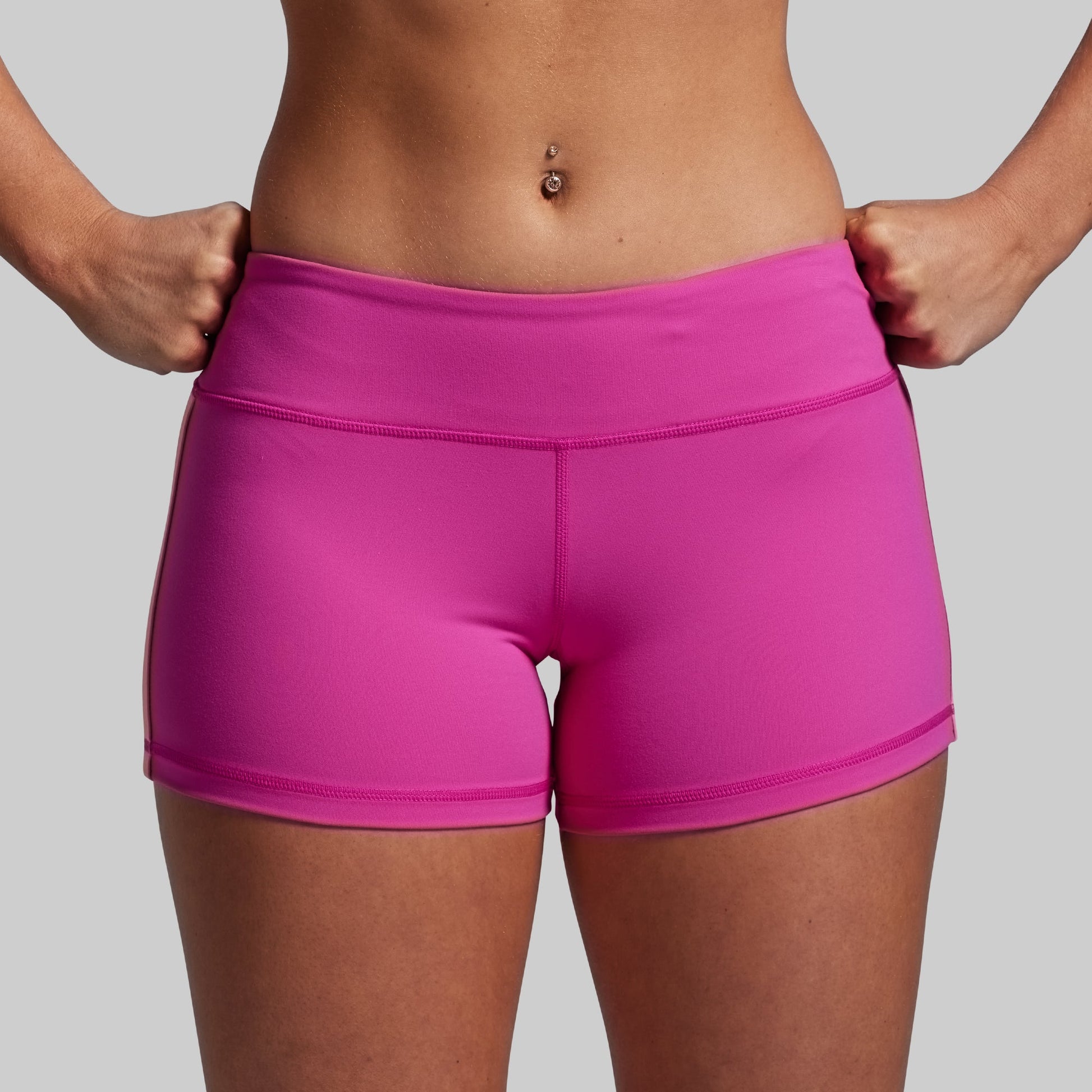 Person wearing bright pink athletic shorts on a plain background