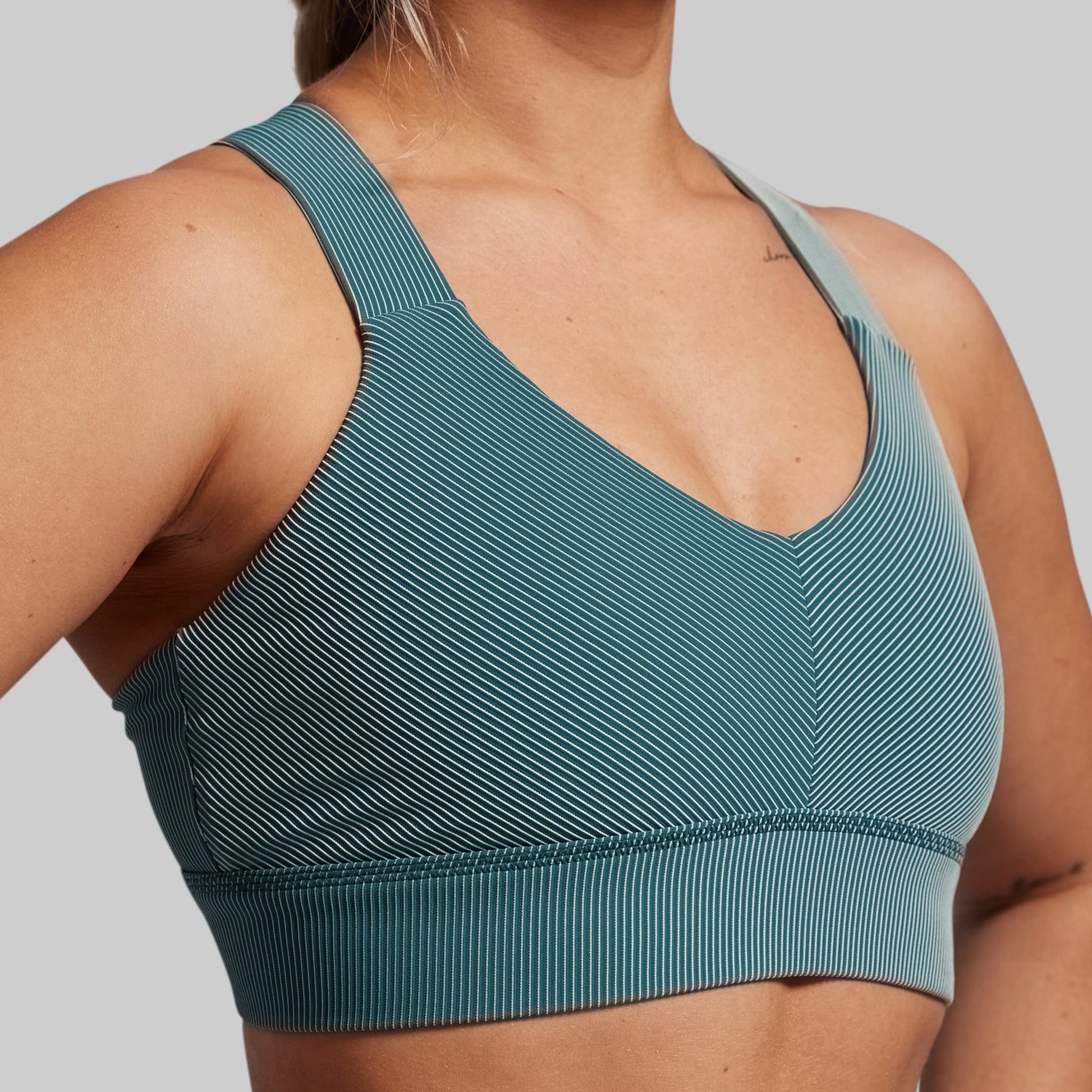 Teal sports bra worn by a person on a plain background