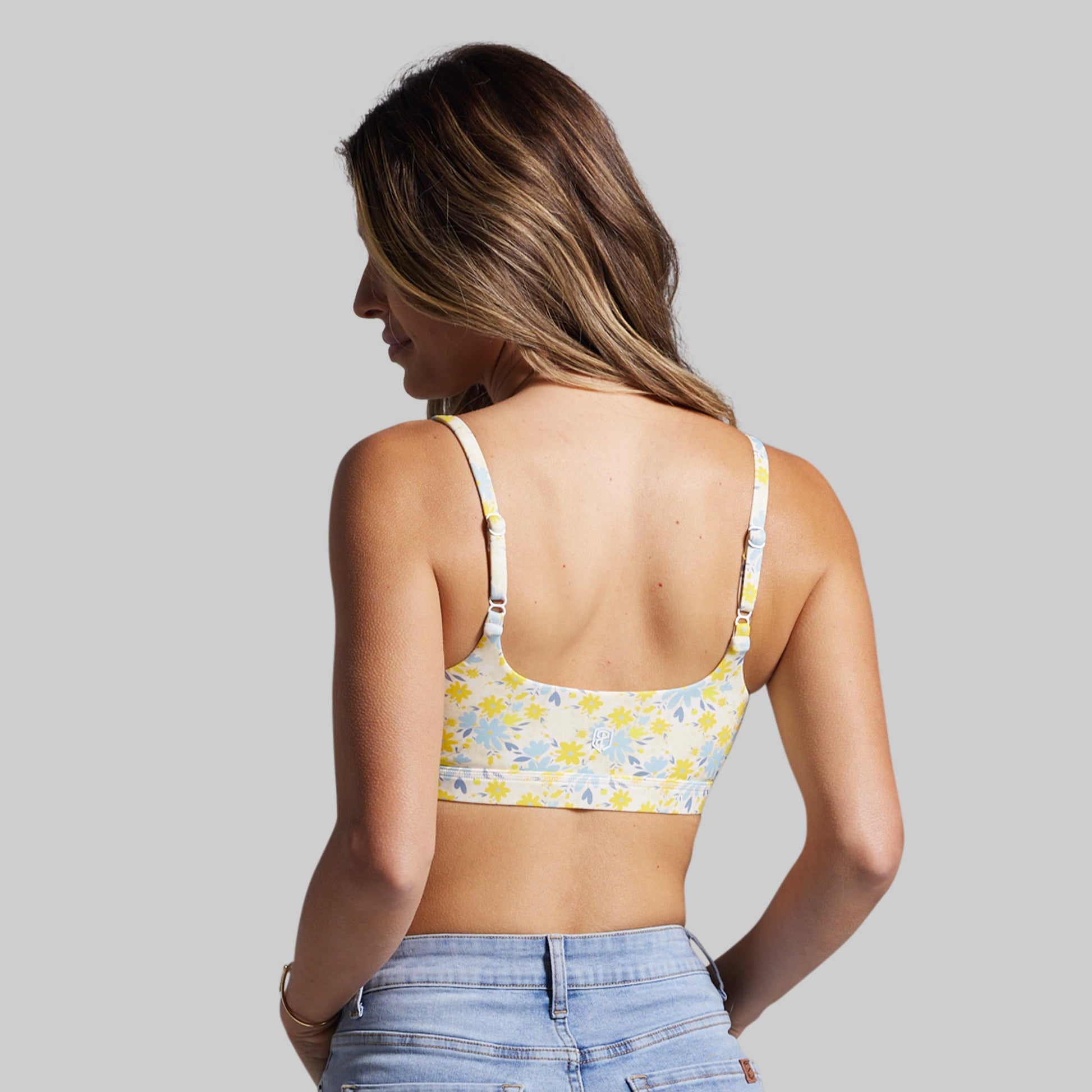 Woman wearing a floral-patterned sports bra against a gray background