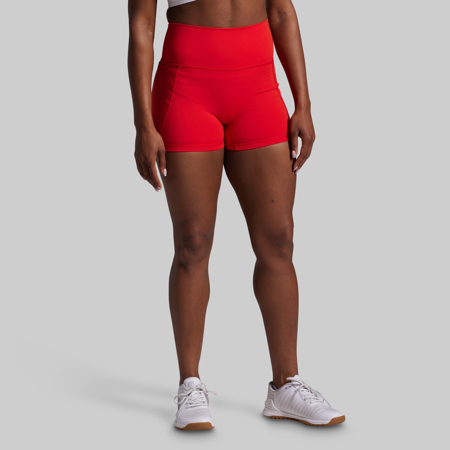 Person wearing red high-waisted shorts on a gray background