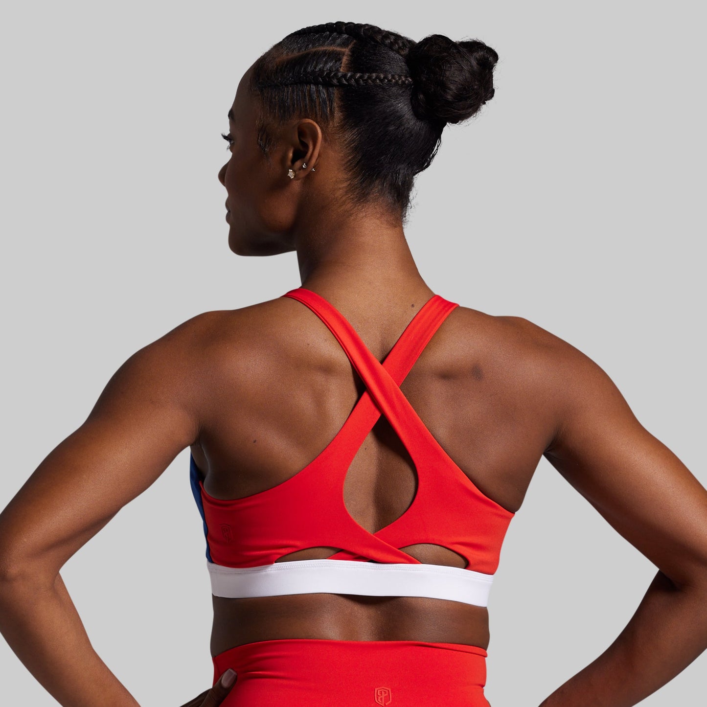 Woman wearing a red sports bra and shorts on a gray background