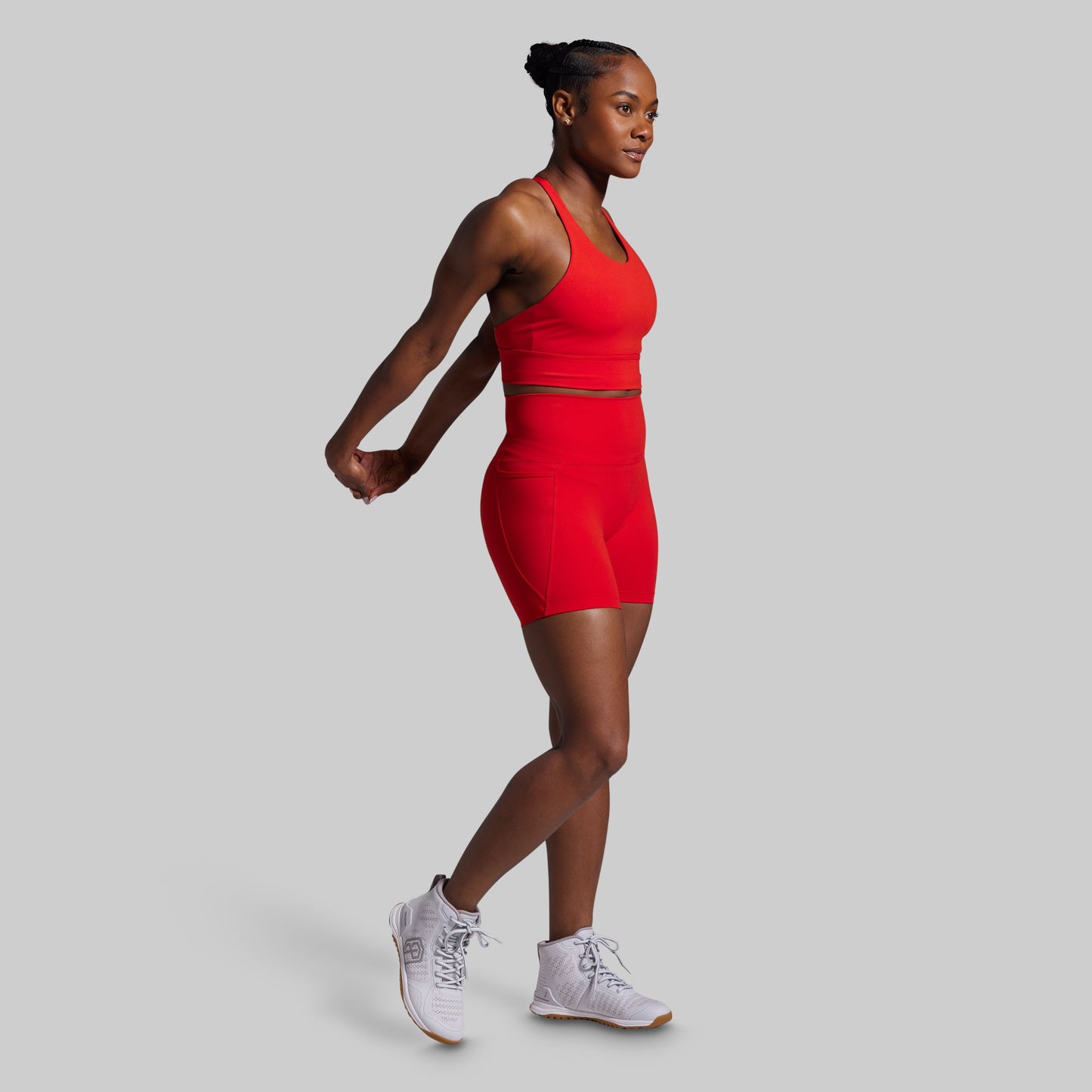 Woman in a red athletic outfit walking on a light gray background