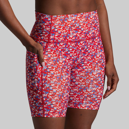 Red floral shorts worn by a person on a gray background