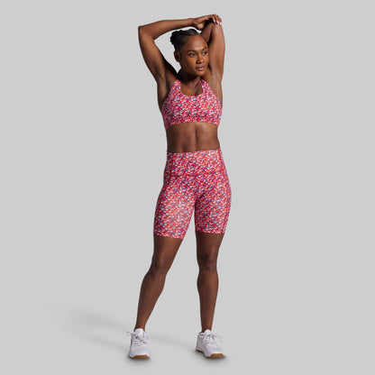 Woman wearing a red and white patterned athletic outfit on a gray background
