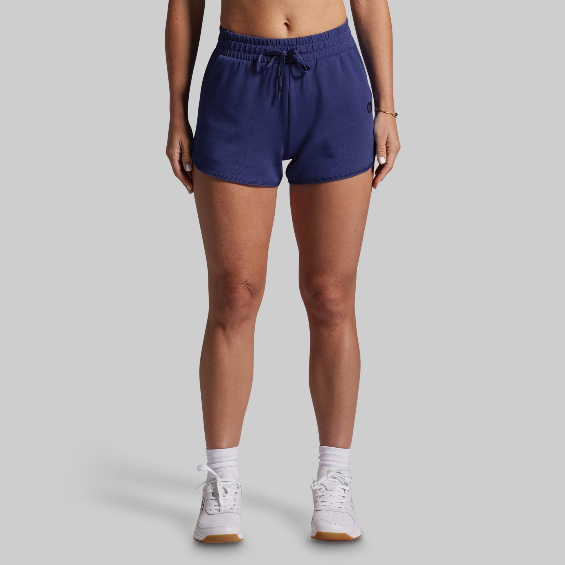 Person wearing navy blue shorts on a gray background