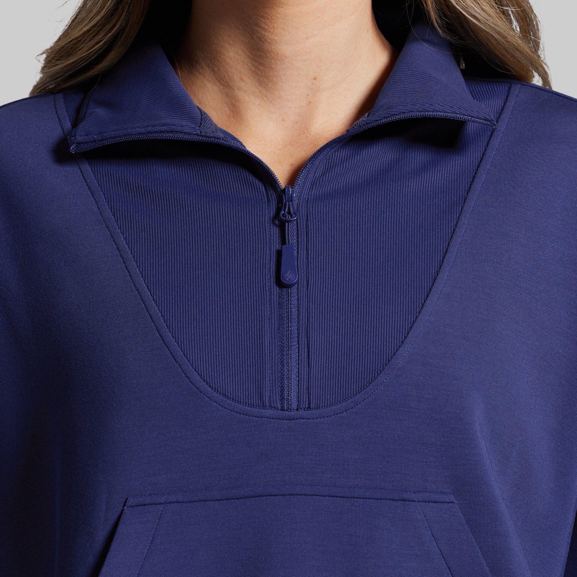 Close-up of a person wearing a blue pullover with a zipper.