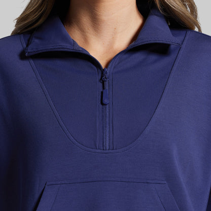 Close-up of a person wearing a blue pullover with a zipper.