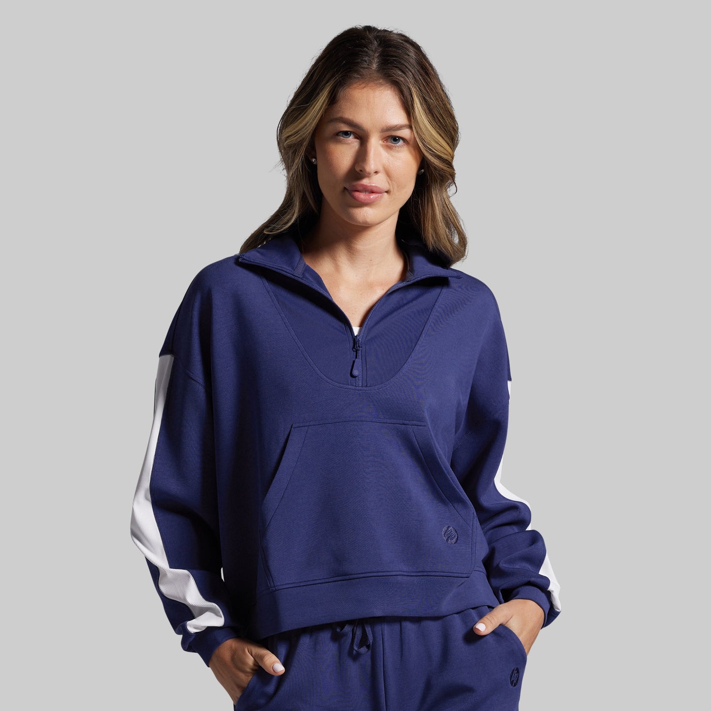 Woman wearing a blue sweatshirt with white stripes on a gray background