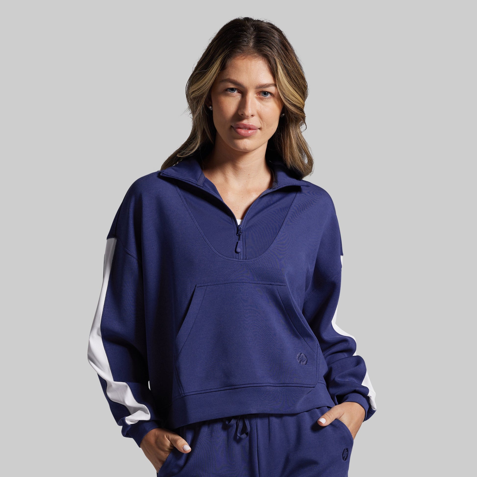Woman wearing a blue sweatshirt with white stripes on a gray background