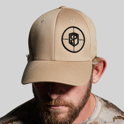 Beige cap with a logo worn by a person against a gray background
