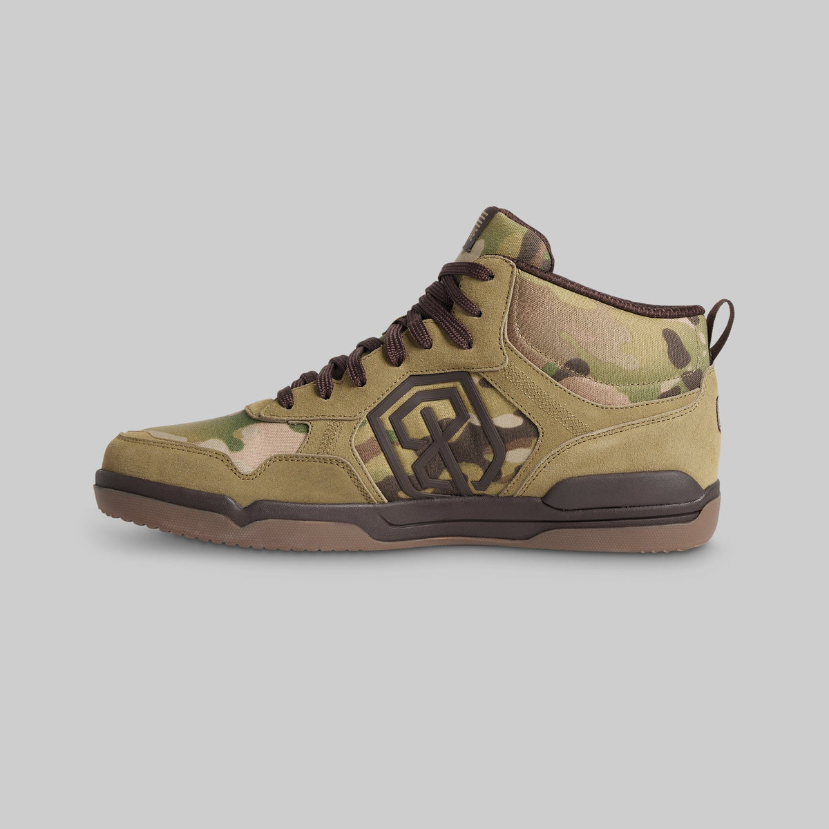 A mid-top sneaker in olive green and brown camouflage with a prominent black geometric logo on the side, set against a solid gray background.