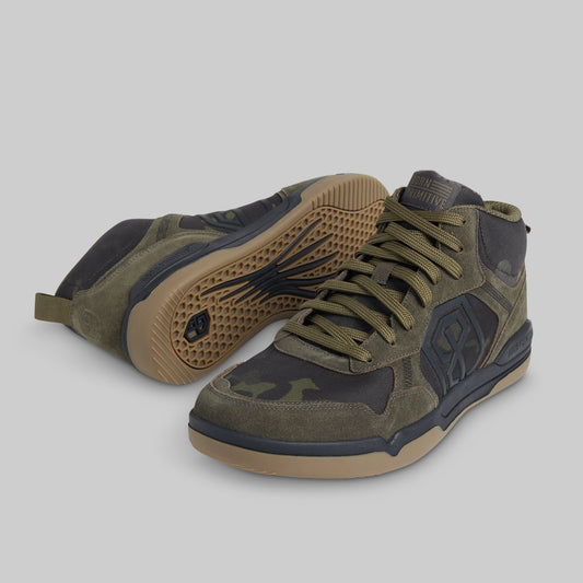A pair of mid-top sneakers in olive green and black with tan soles, shown on a solid gray background.