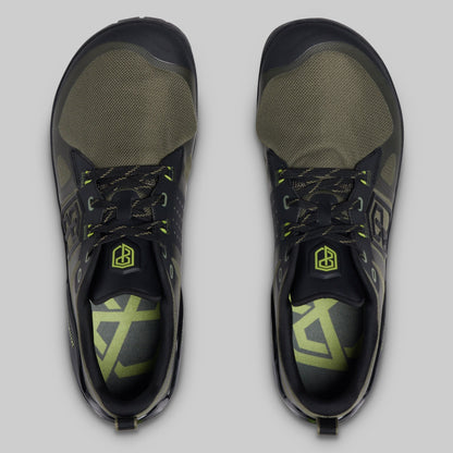 A pair of athletic minimalist training shoes shown from a top-down view on a light gray background. The shoes feature a black and olive green colorway with neon yellow-green accents on the laces, logo, and insole.