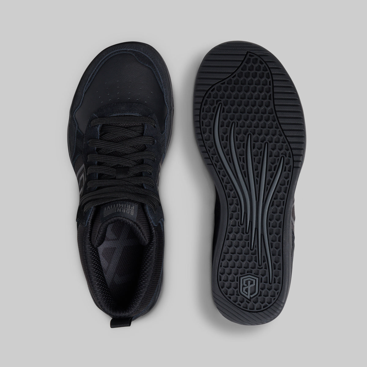 A pair of black athletic sneakers shown from a top-down view, with one shoe displaying the side and the other showing the textured outsole, set against a solid light gray background.
