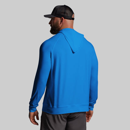 Person wearing a blue hoodie and black cap on a gray background