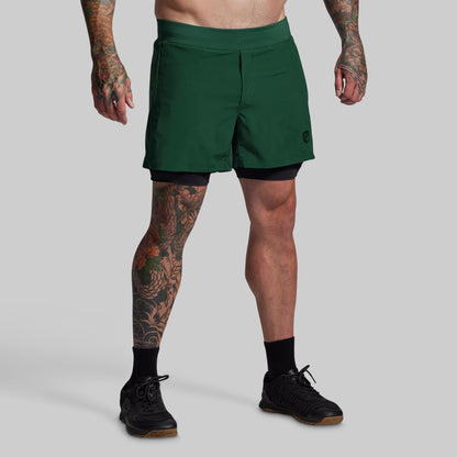 Person wearing green athletic shorts on a gray background